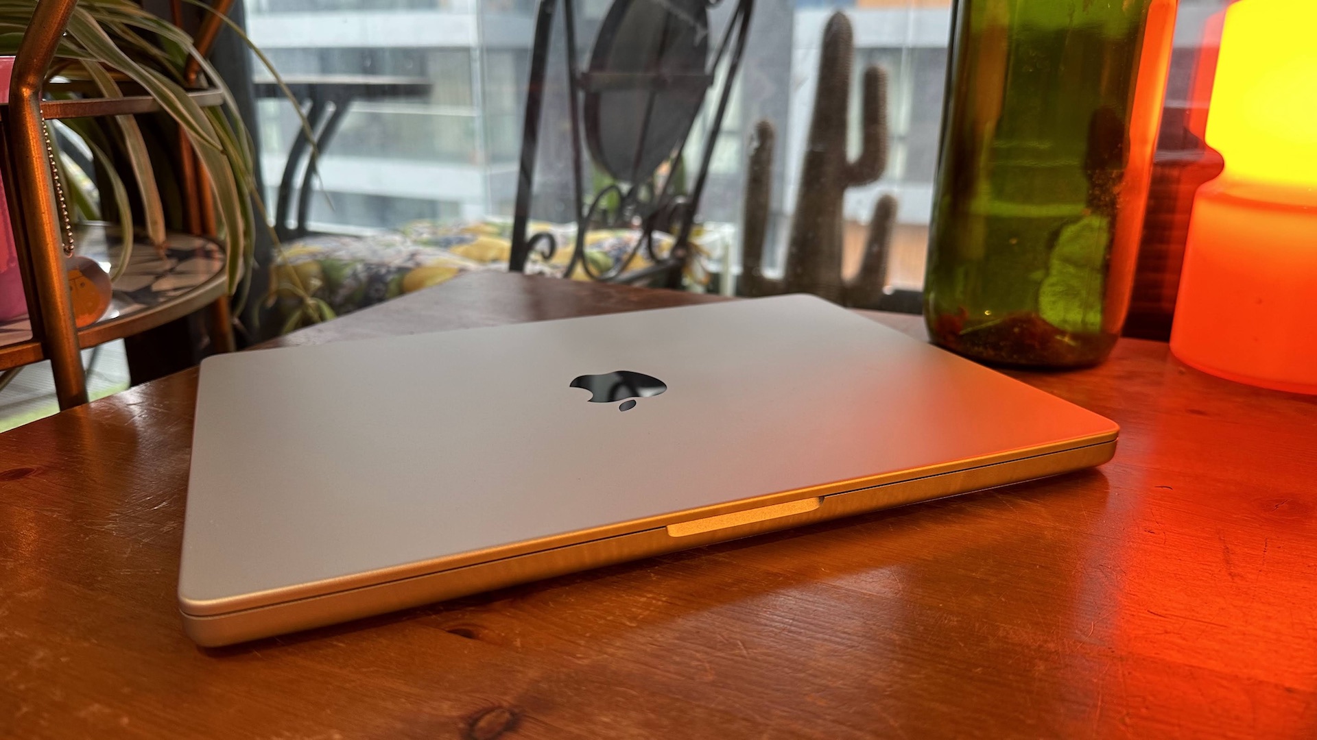 A 2023 14-inch MacBook Pro on a wooden counter, near a retro lamp.